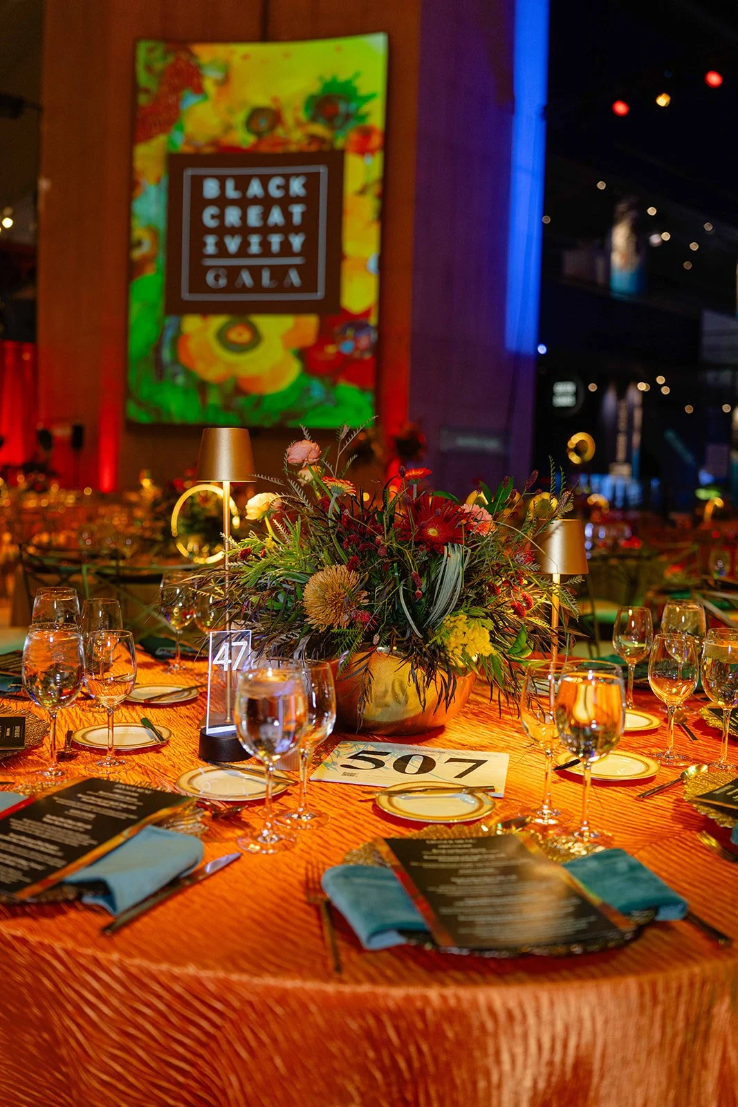 Orange linen tablescape with florals and lamps at the Black Creativity Gala