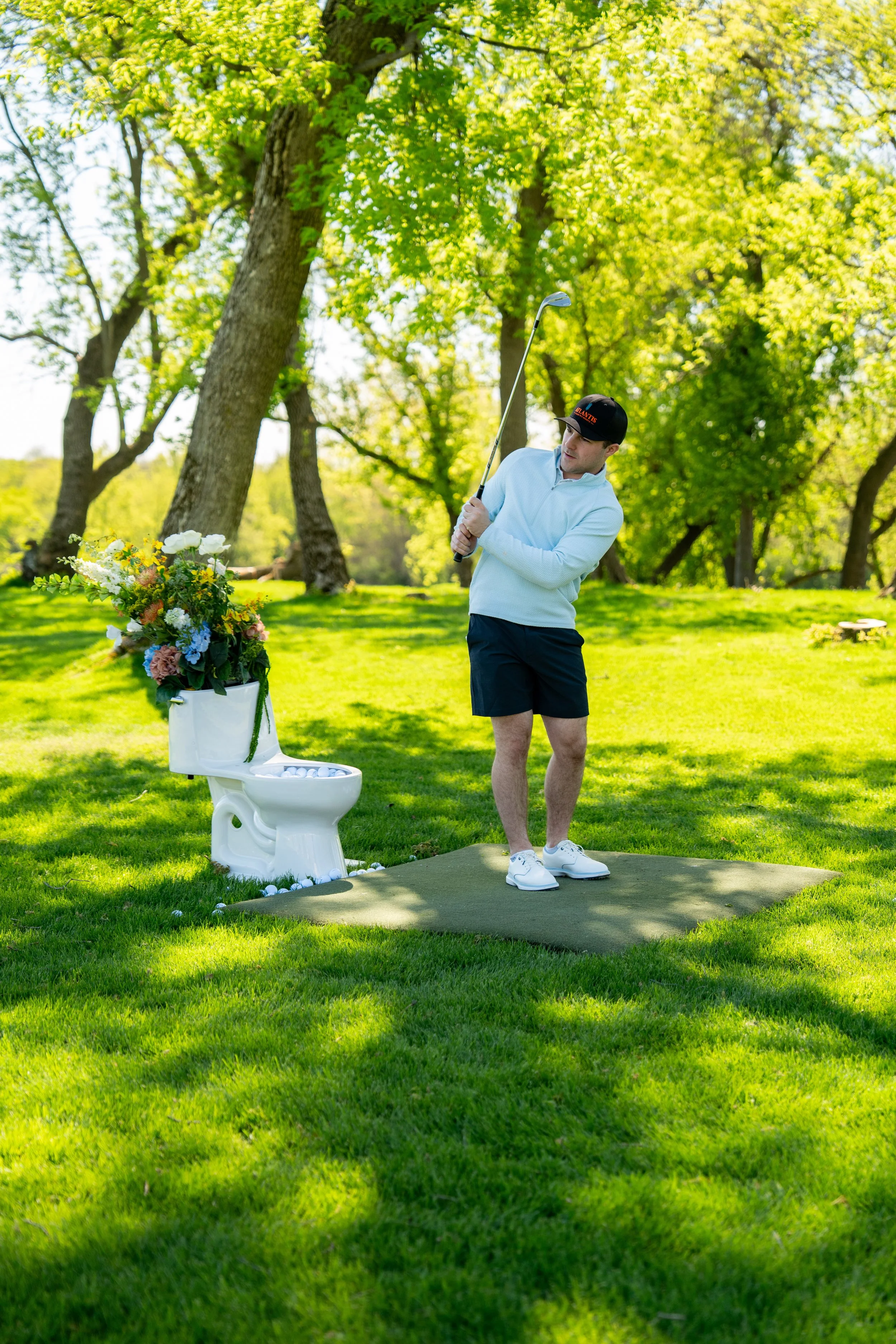 Golfer mid-swing beside floral Kohler toilet installation at the Chicago Bowl