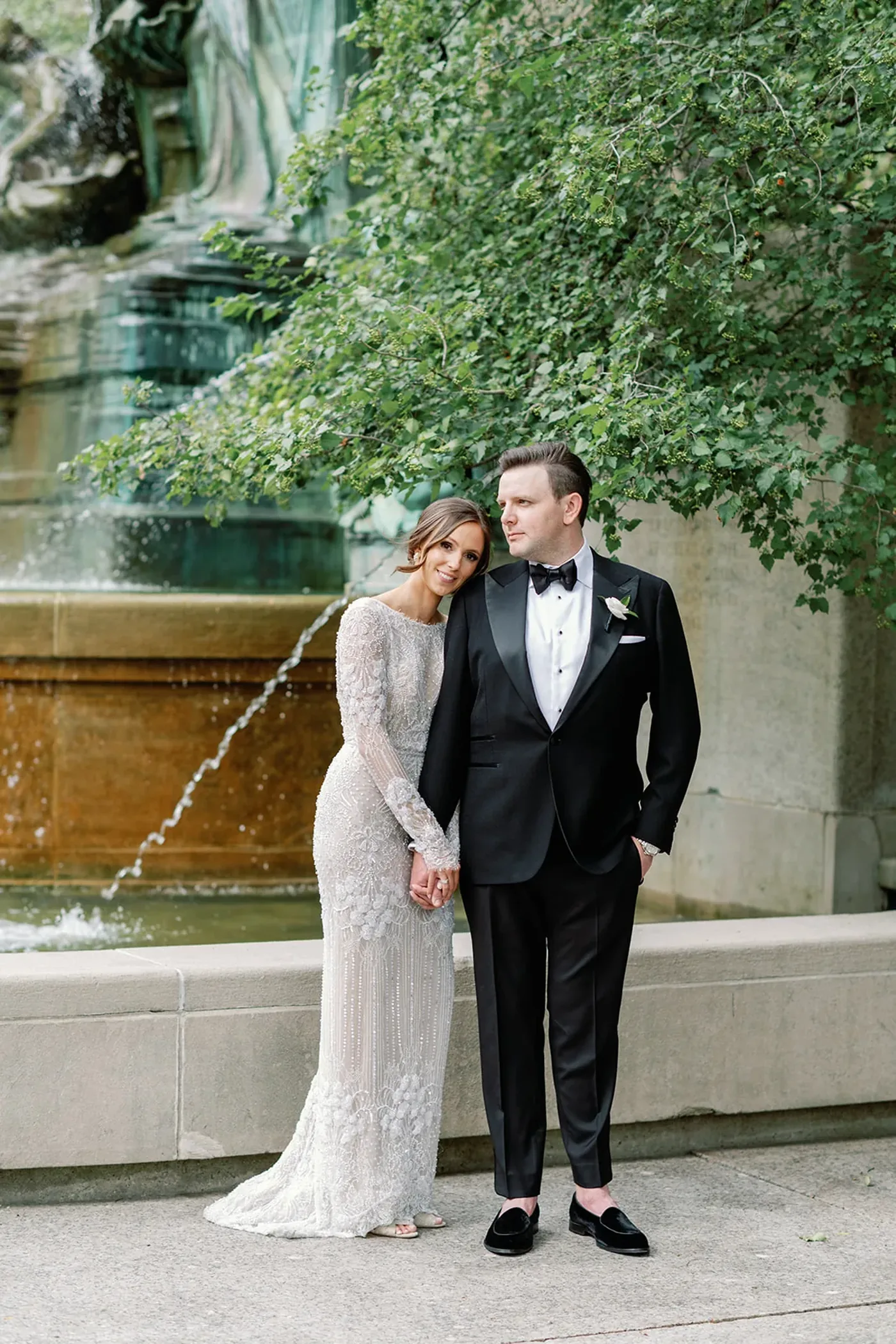 Bride and groom in formal attire beside a stone fountain at a Michigan Avenue Events celebration