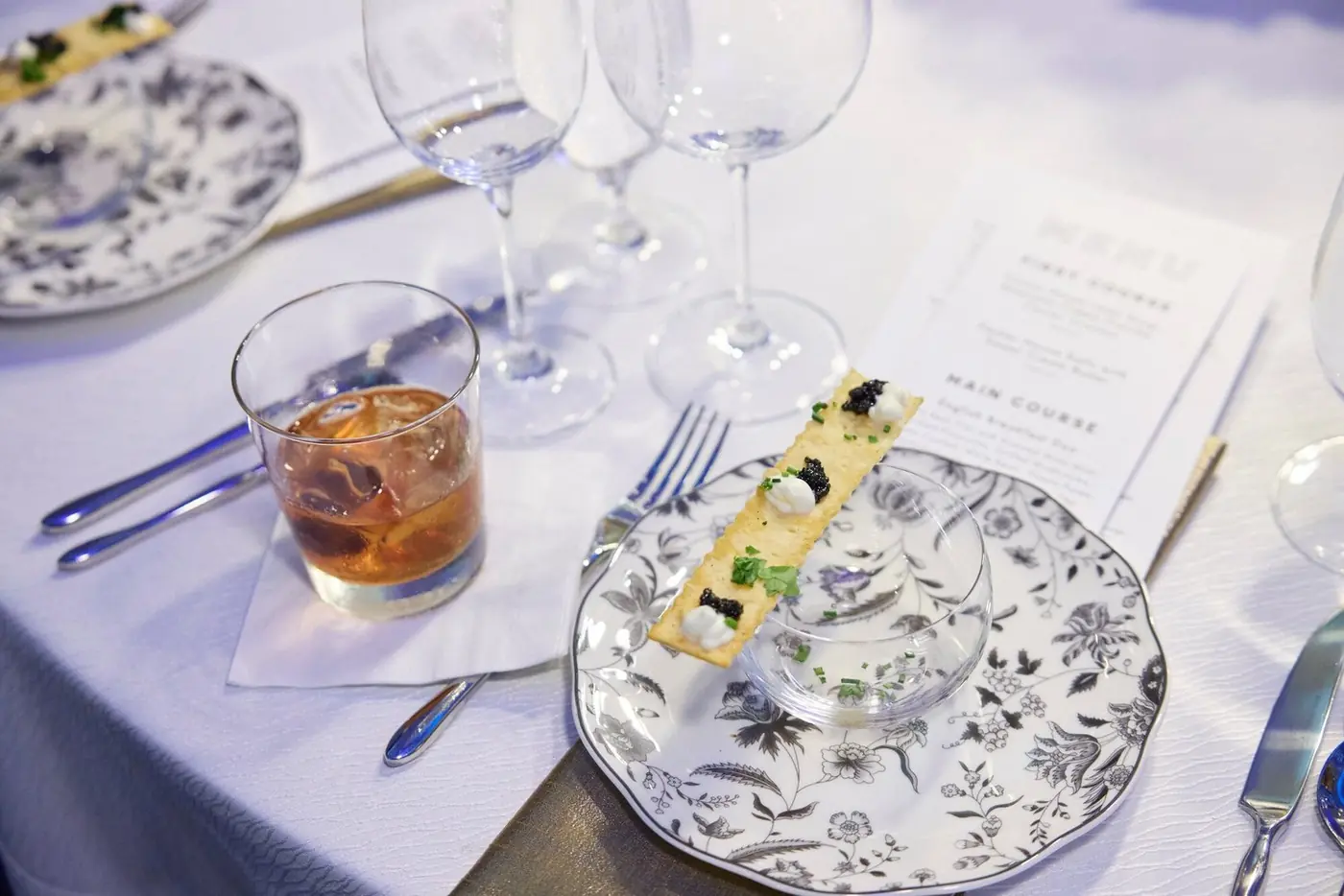 Caviar cracker appetizer and cocktail at a formal place setting