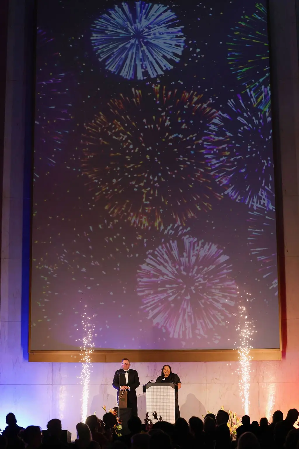 Stage presenters with cold-spark fountains and fireworks screen