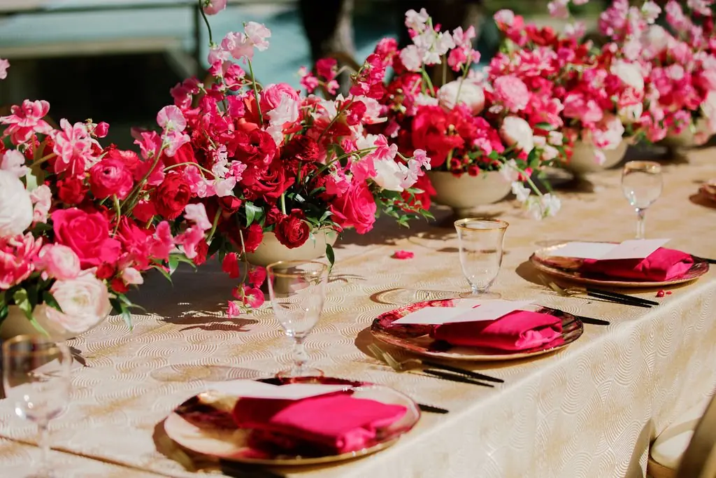 Rose-gold chargers and pink napkins along a floral brunch table