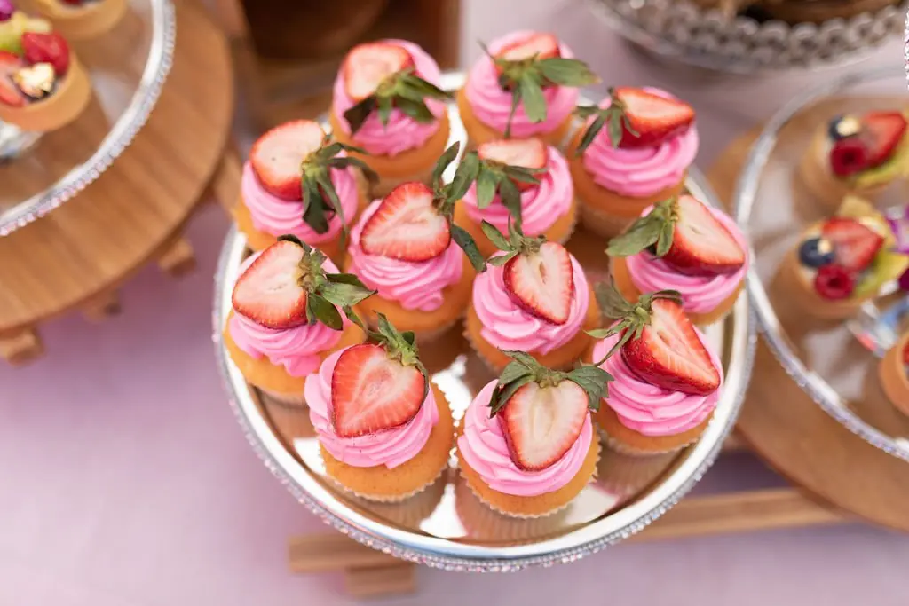 Pink-frosted strawberry cupcakes on a silver platter