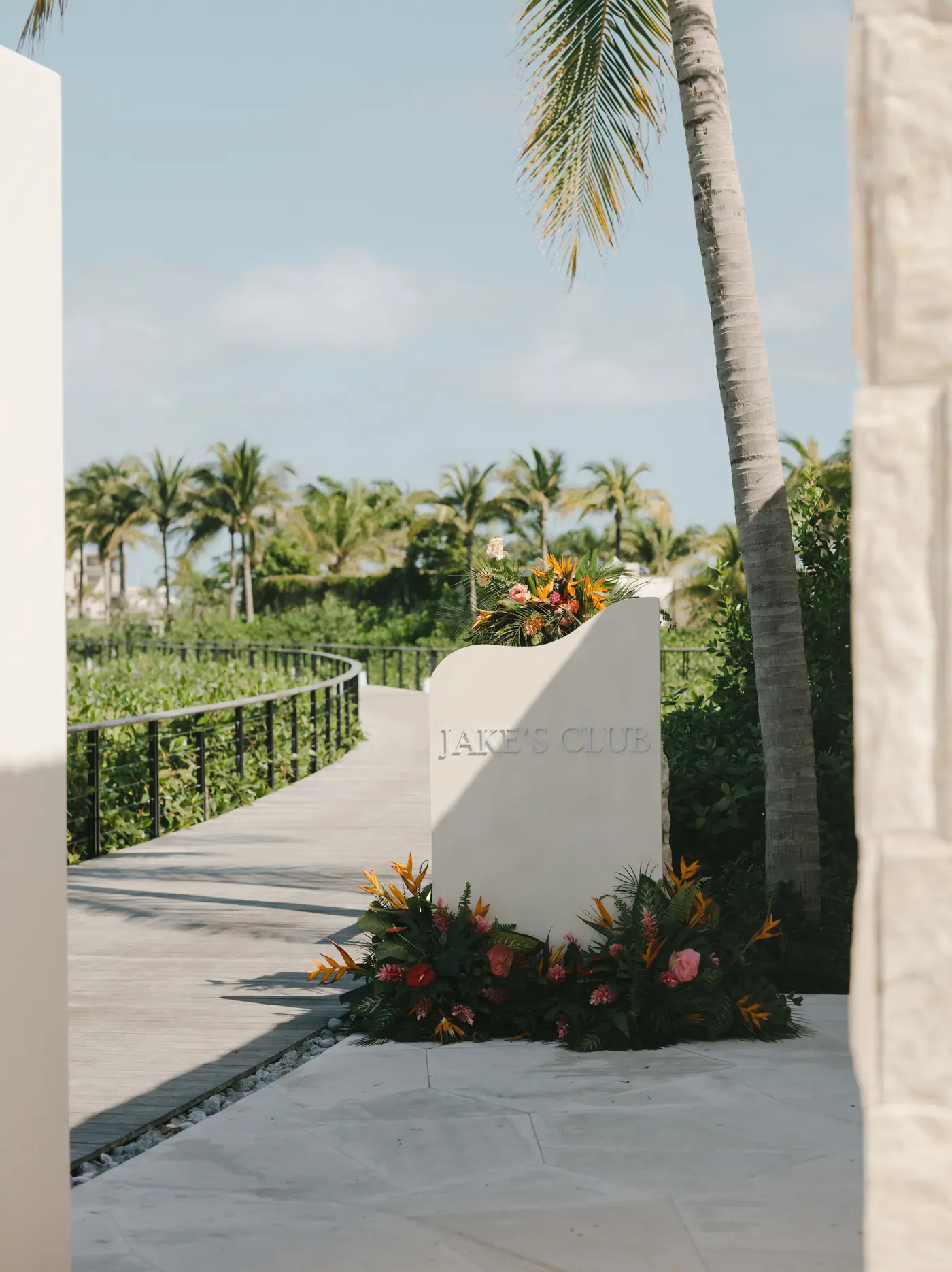 Stone pathway lined with tropical florals leading to a ceremony lawn at a destination wedding planned by Michigan Avenue Events