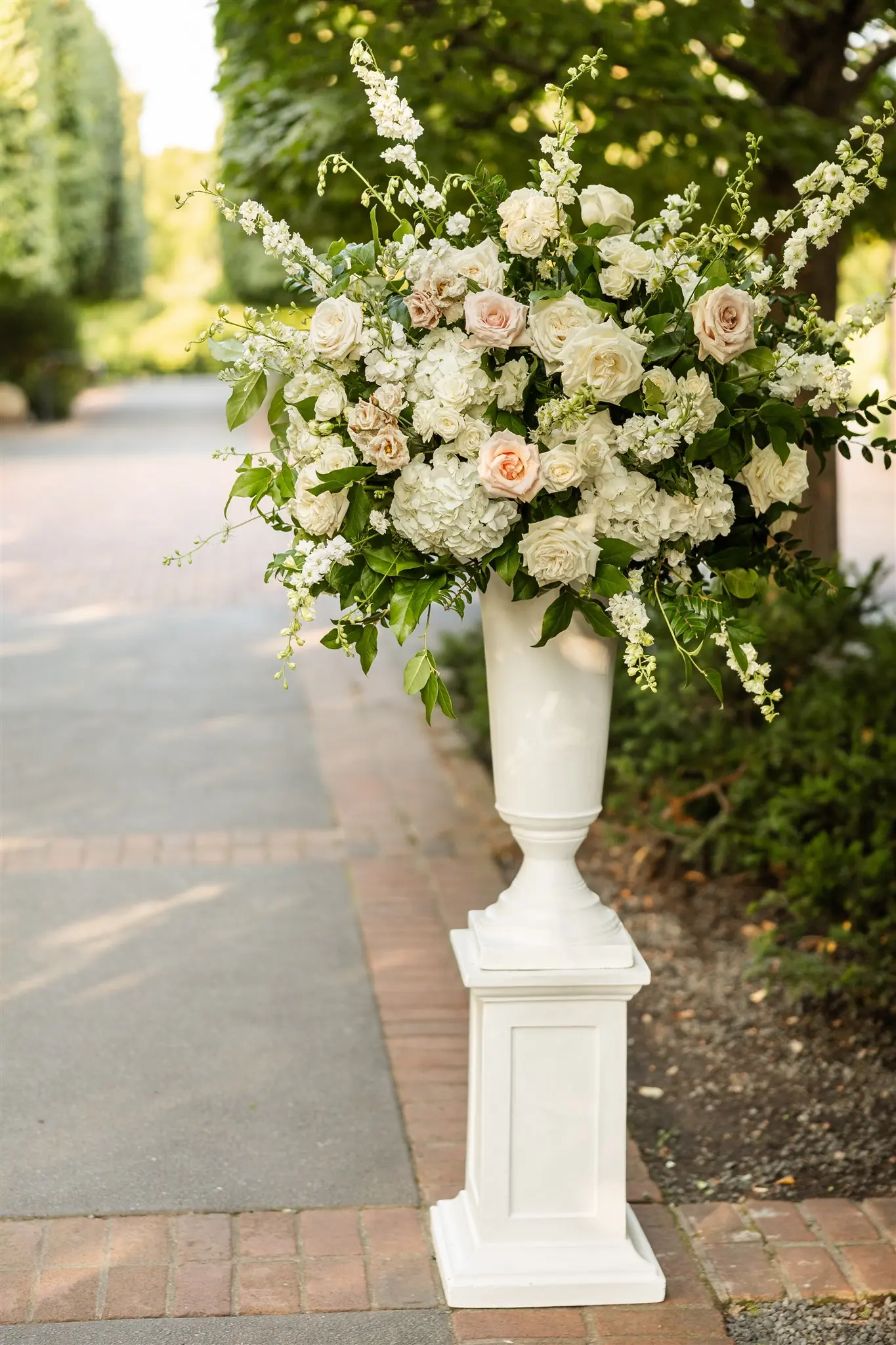 Towering white garden roses and greenery in a classical urn at a wedding ceremony planned by Michigan Avenue Events