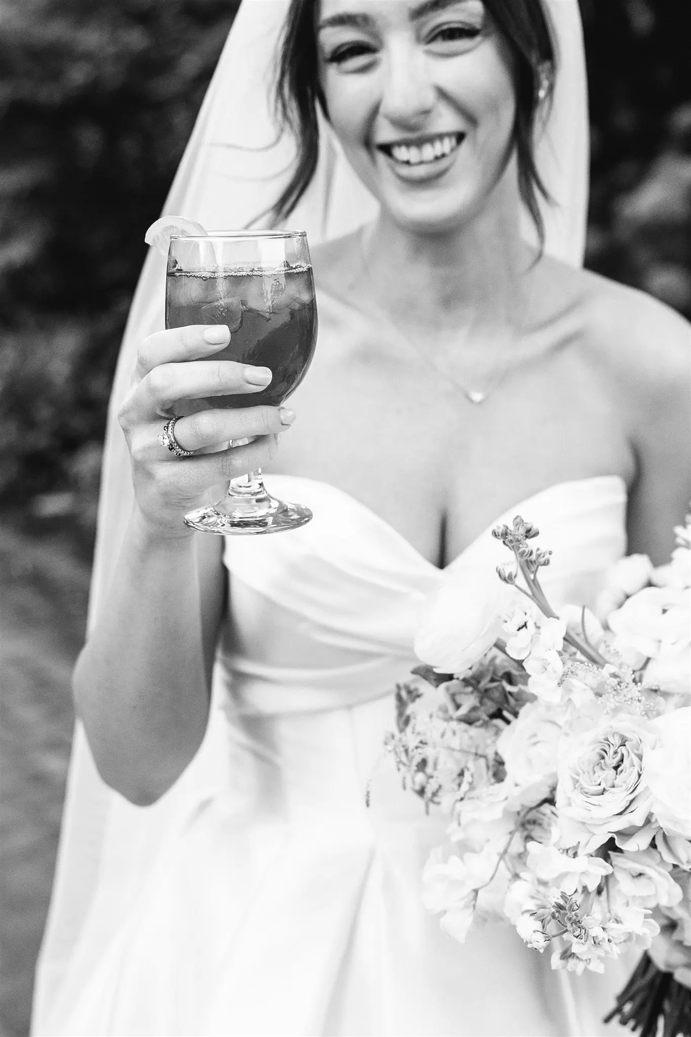 Black-and-white portrait of a laughing bride raising a glass beside her bouquet at a Michigan Avenue Events wedding