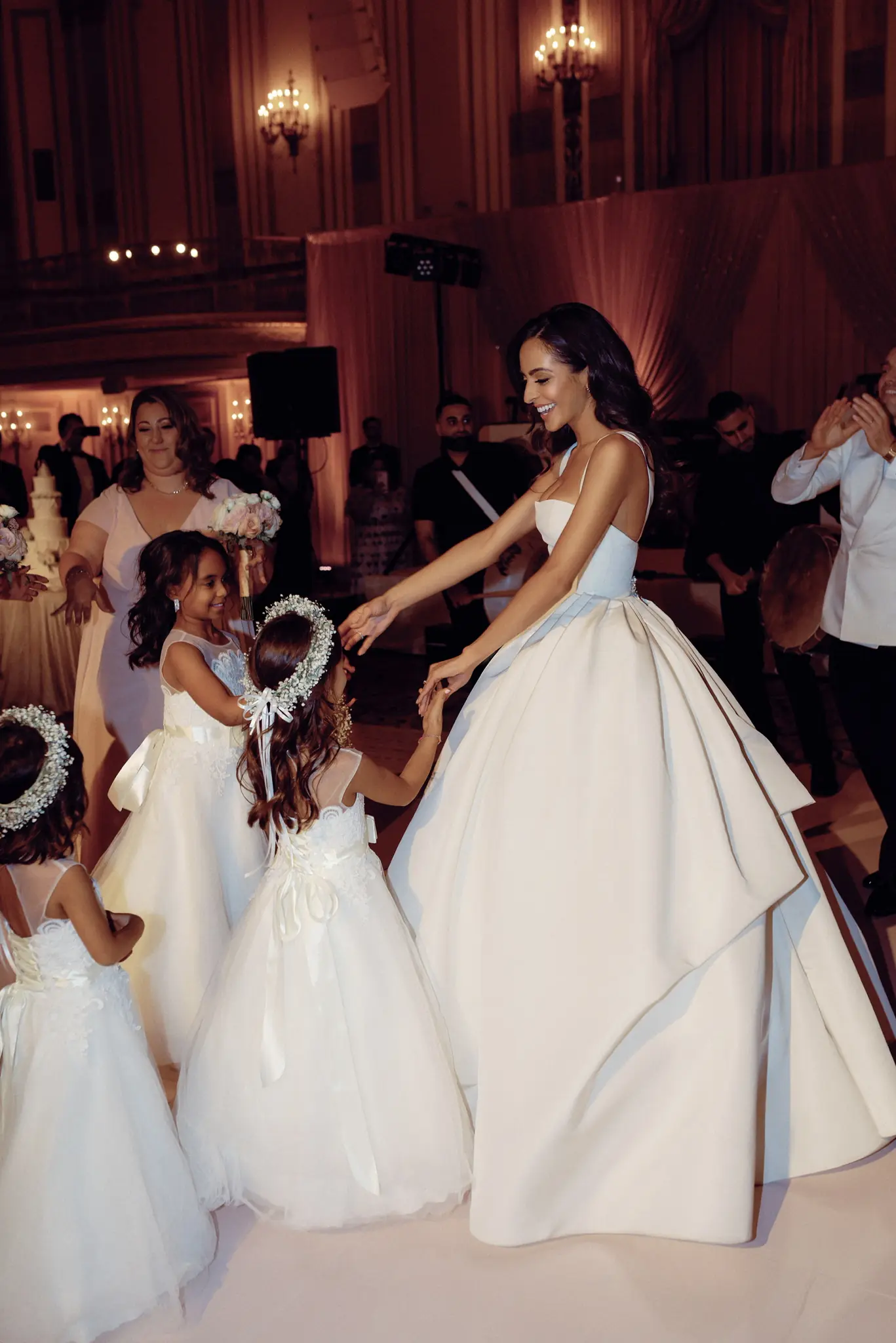 Bride greeting flower girls on a ballroom dance floor at a wedding planned by Michigan Avenue Events
