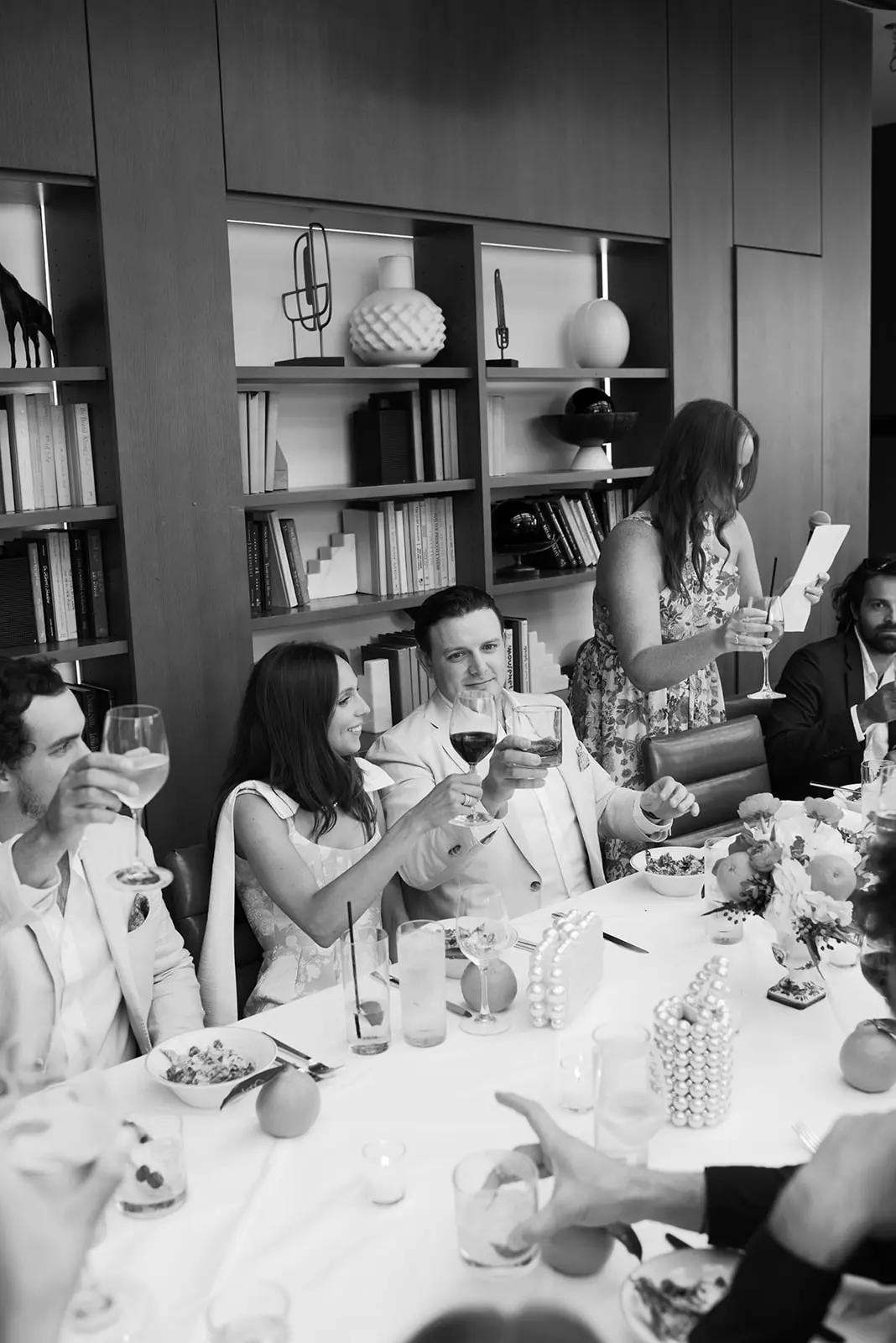 Black-and-white view of guests toasting at a long dinner table during a Michigan Avenue Events wedding