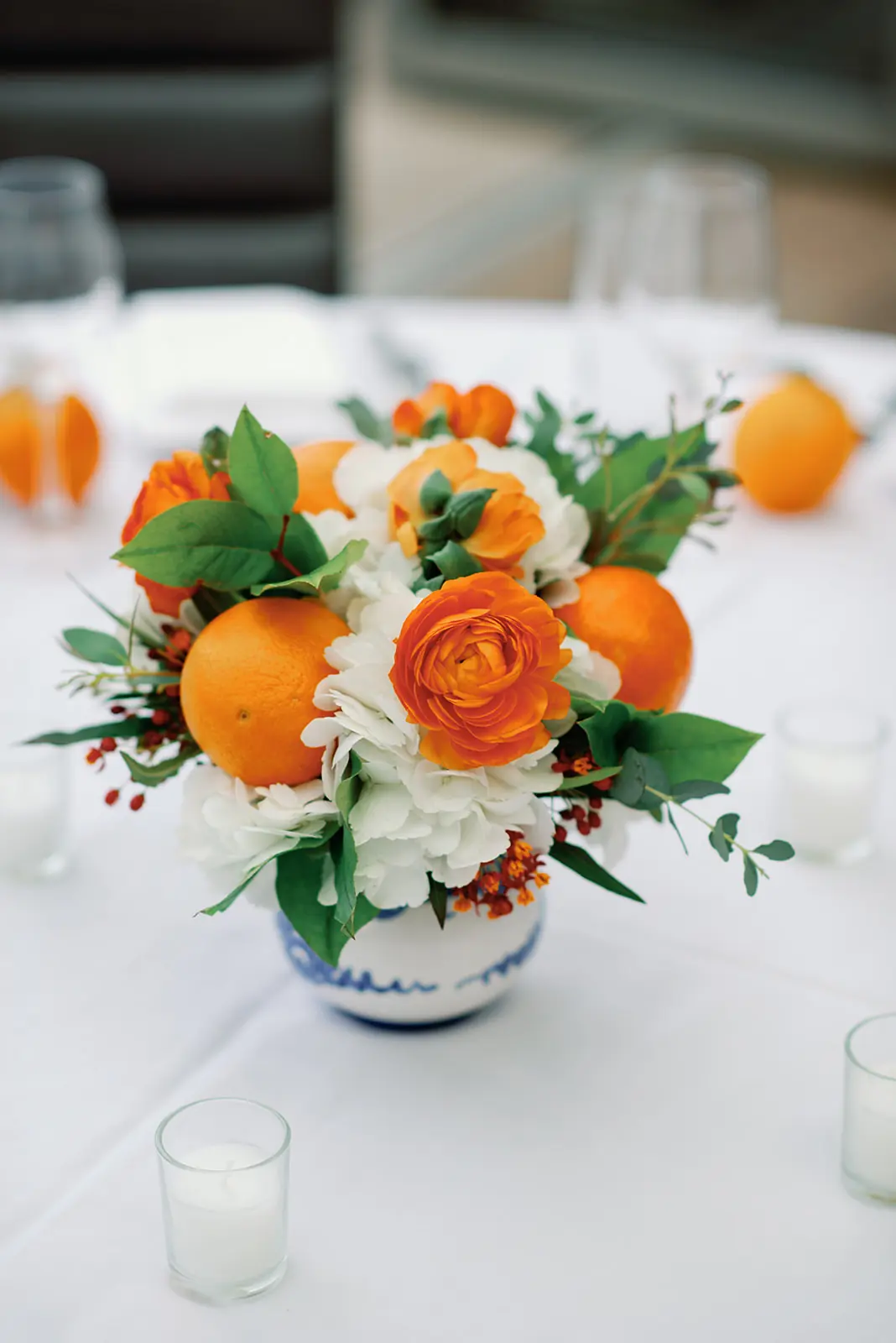 Orange and white floral centerpiece with votives on a reception table at a wedding planned by Michigan Avenue Events