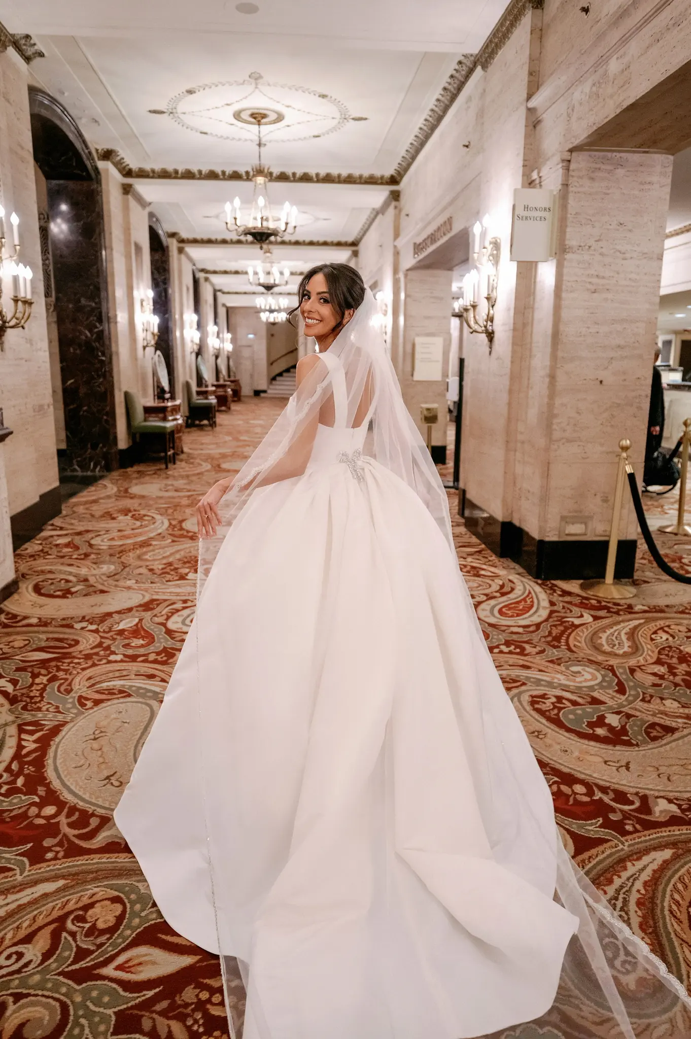 Bride walking a grand hotel corridor with her train trailing behind at a Chicago wedding planned by Michigan Avenue Events