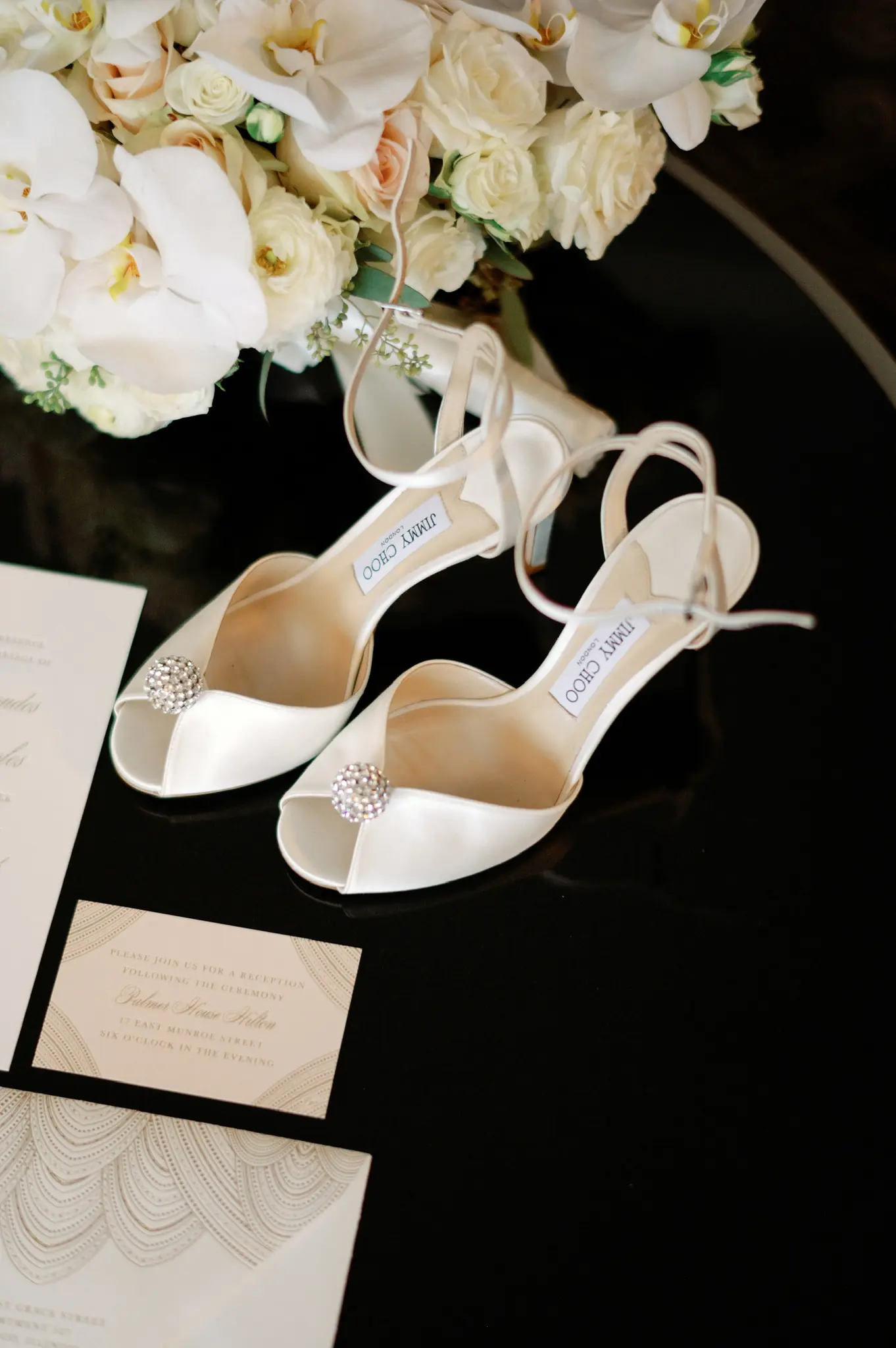 Bridal heels and stationery arranged on a black table at a wedding planned by Michigan Avenue Events