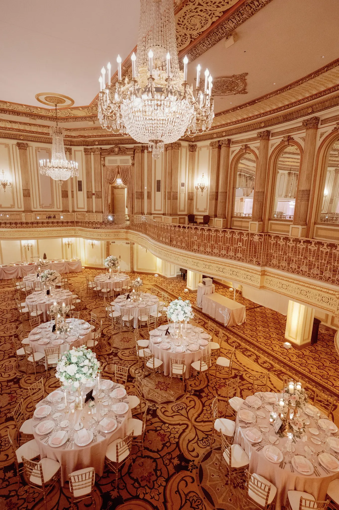 Chandelier-lit ballroom with white floral centerpieces set for a reception planned by Michigan Avenue Events
