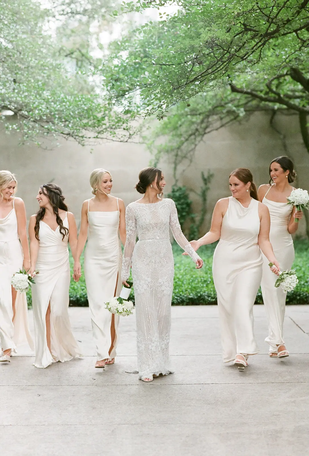 Bridesmaids in ivory gowns walking a rooftop garden at a Chicago wedding planned by Michigan Avenue Events