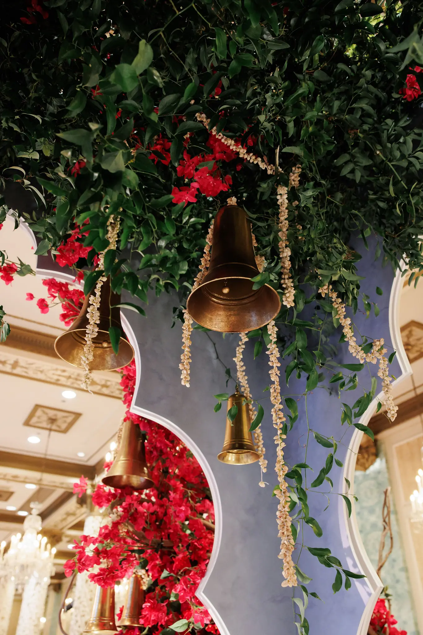 Brass ceremony bells hung among red florals and greenery at a wedding planned by Michigan Avenue Events
