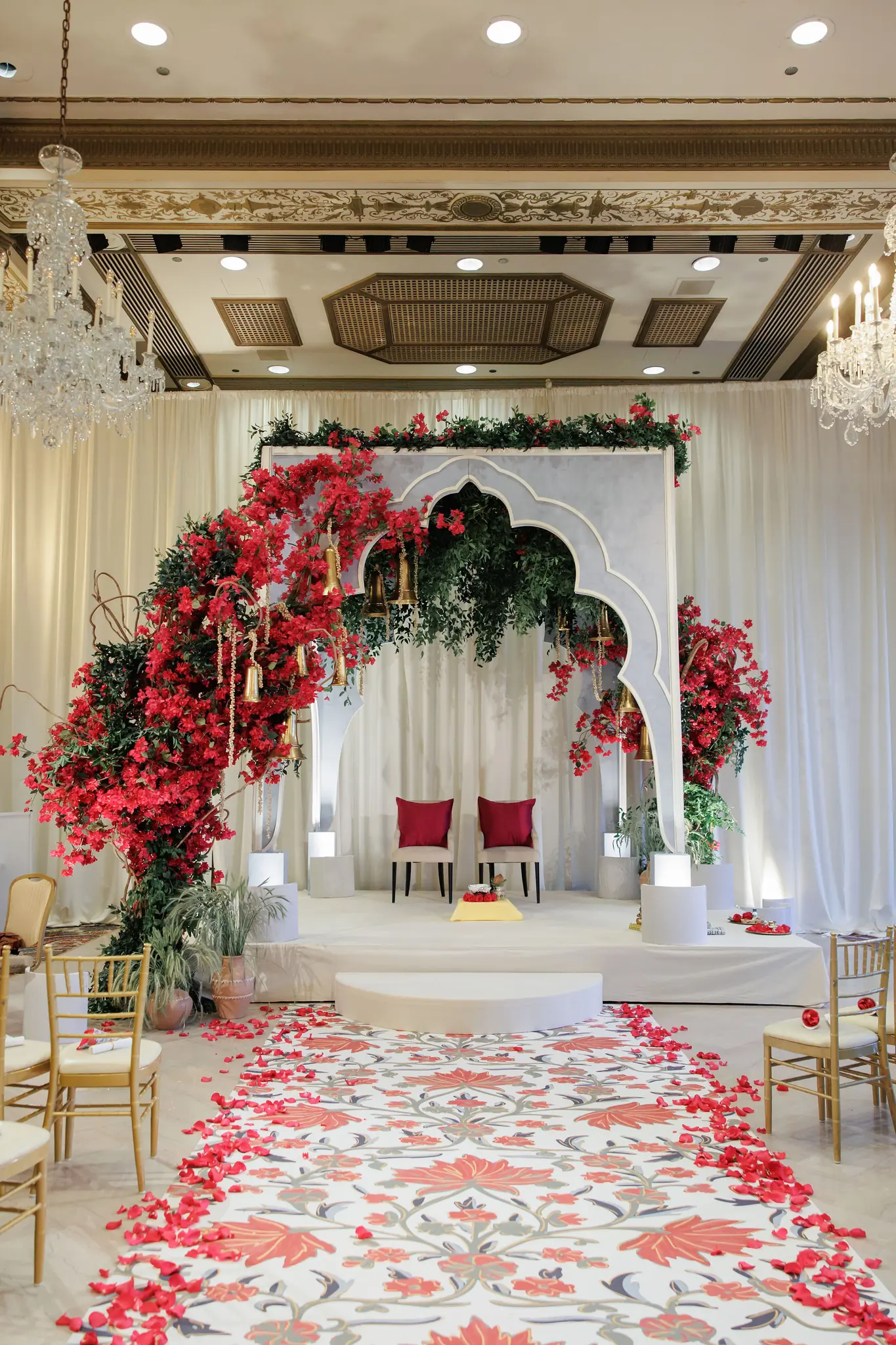 Red-petal aisle leading to a floral mandap beneath a ballroom's coffered ceiling at a wedding planned by Michigan Avenue Events