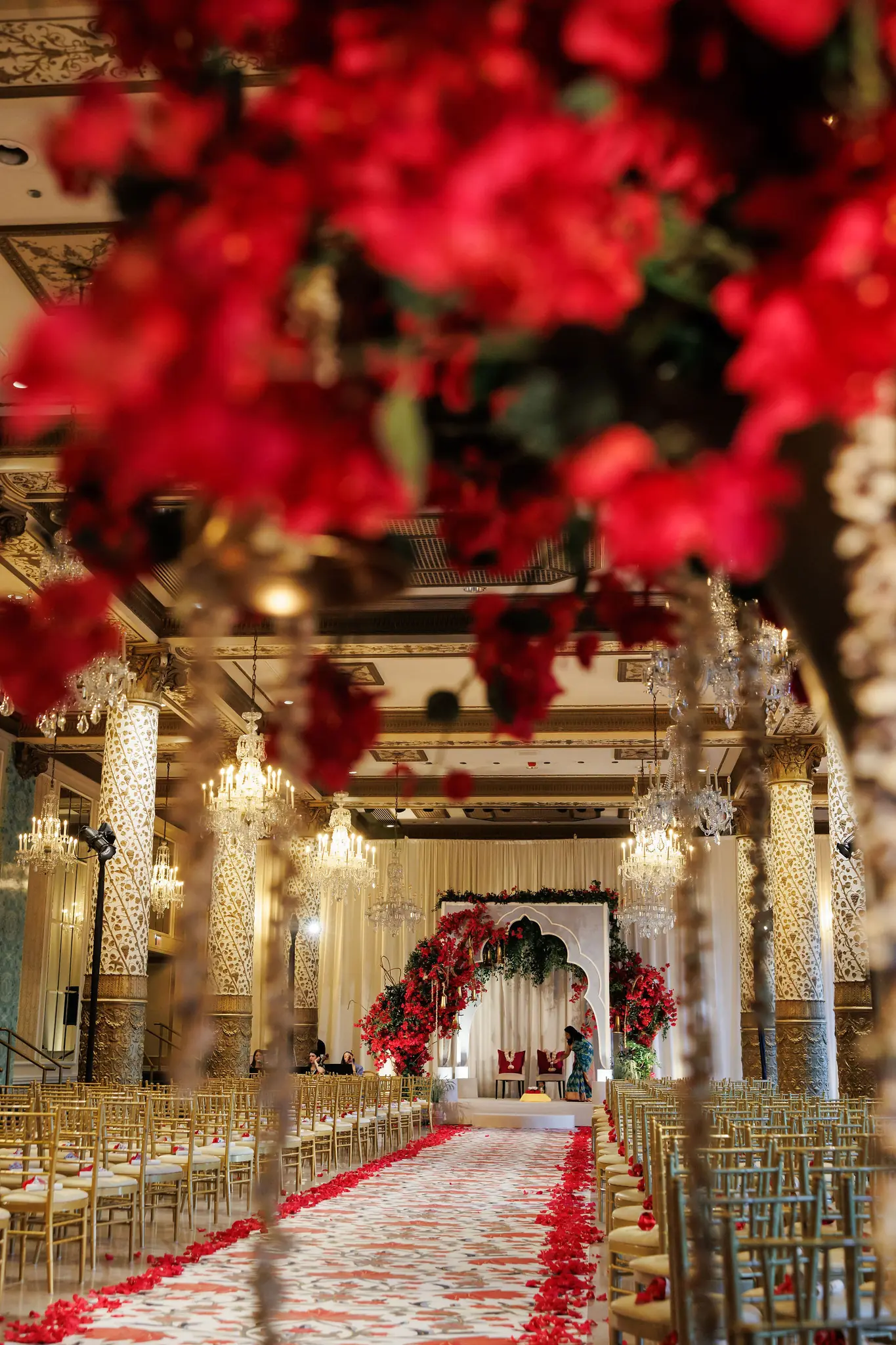 Red floral canopy over a ceremony aisle in a gilded ballroom at a wedding planned by Michigan Avenue Events
