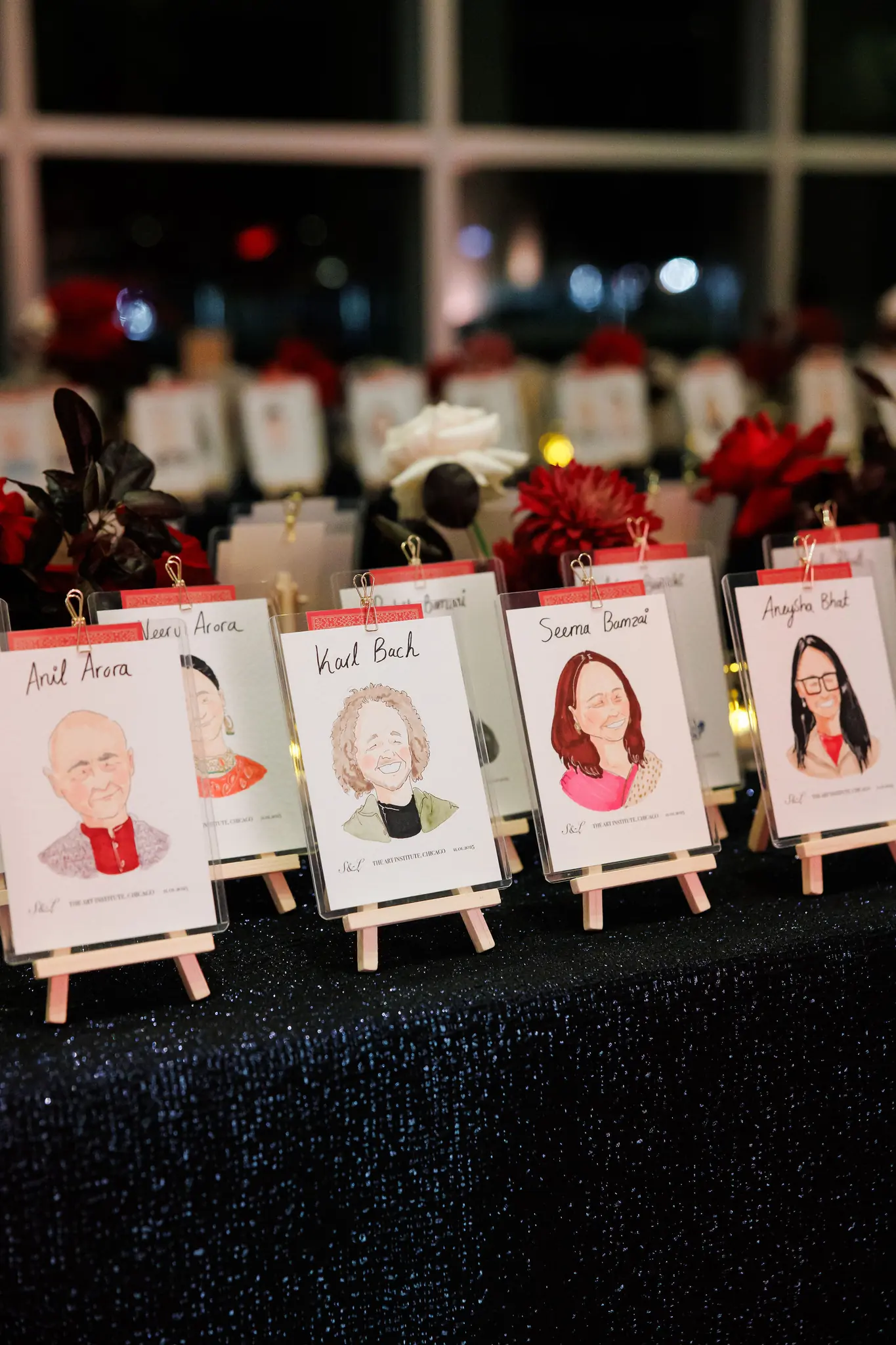 Illustrated escort cards on easels with burgundy roses at a reception planned by Michigan Avenue Events