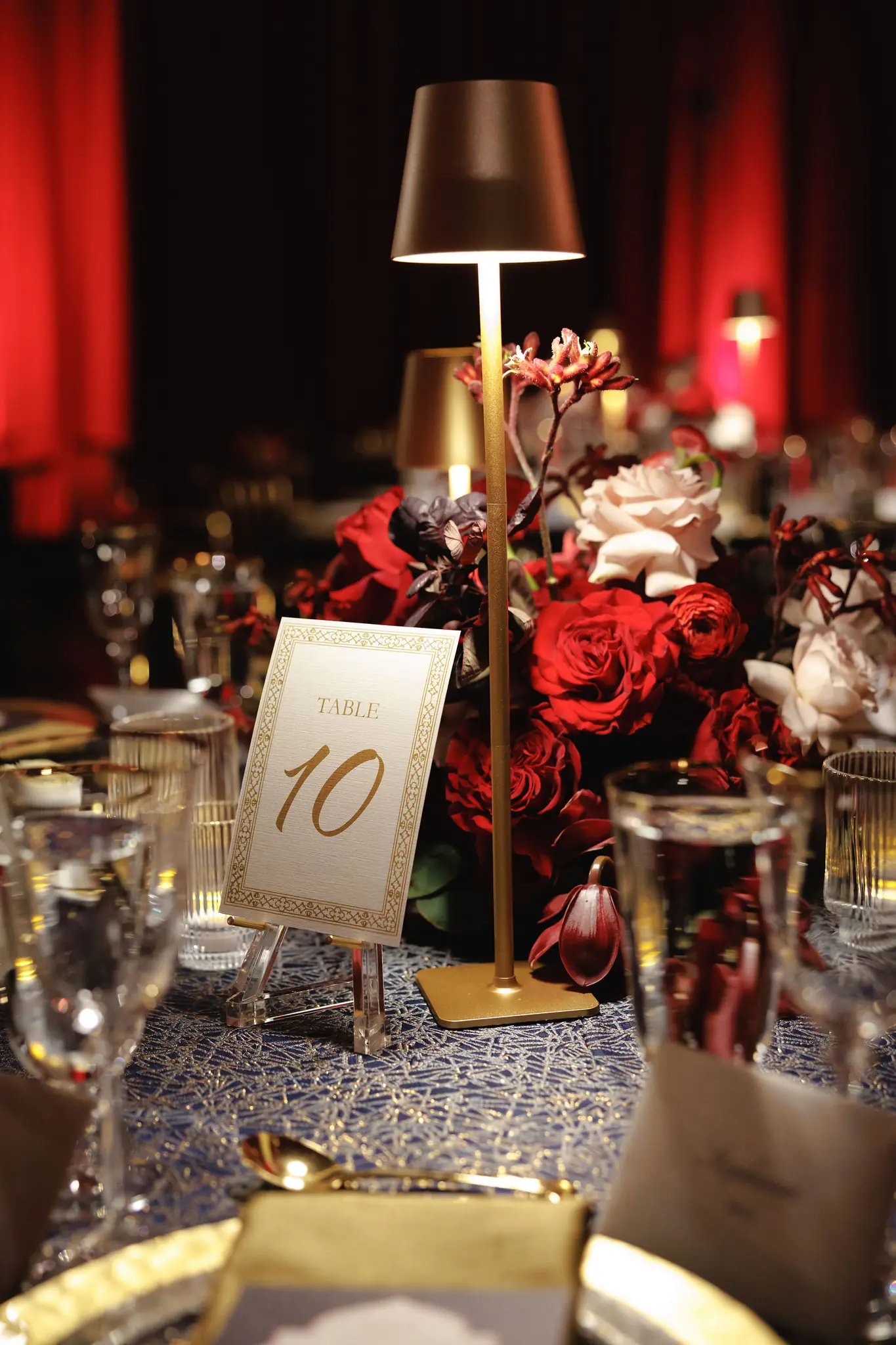 Table number, lamp, and red roses on a reception table at a wedding planned by Michigan Avenue Events