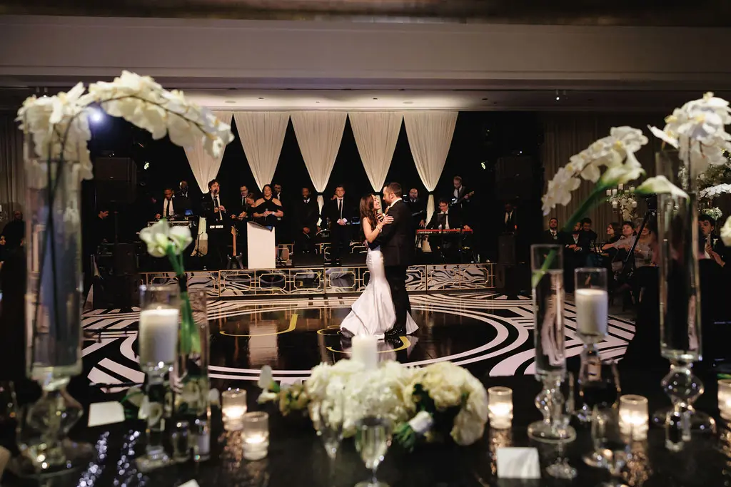 Black-and-white view of a ballroom reception with towering white florals planned by Michigan Avenue Events