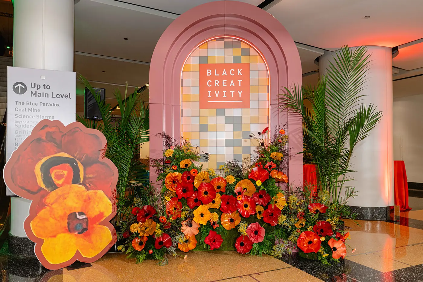 Black Creativity Gala entrance with bold floral sculptures and a mosaic arch, produced by Michigan Avenue Events