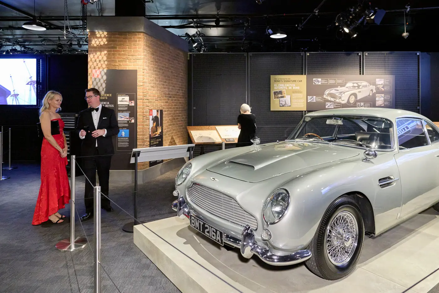 Hosts beside a classic silver sports car at the 007 Science gala produced by Michigan Avenue Events