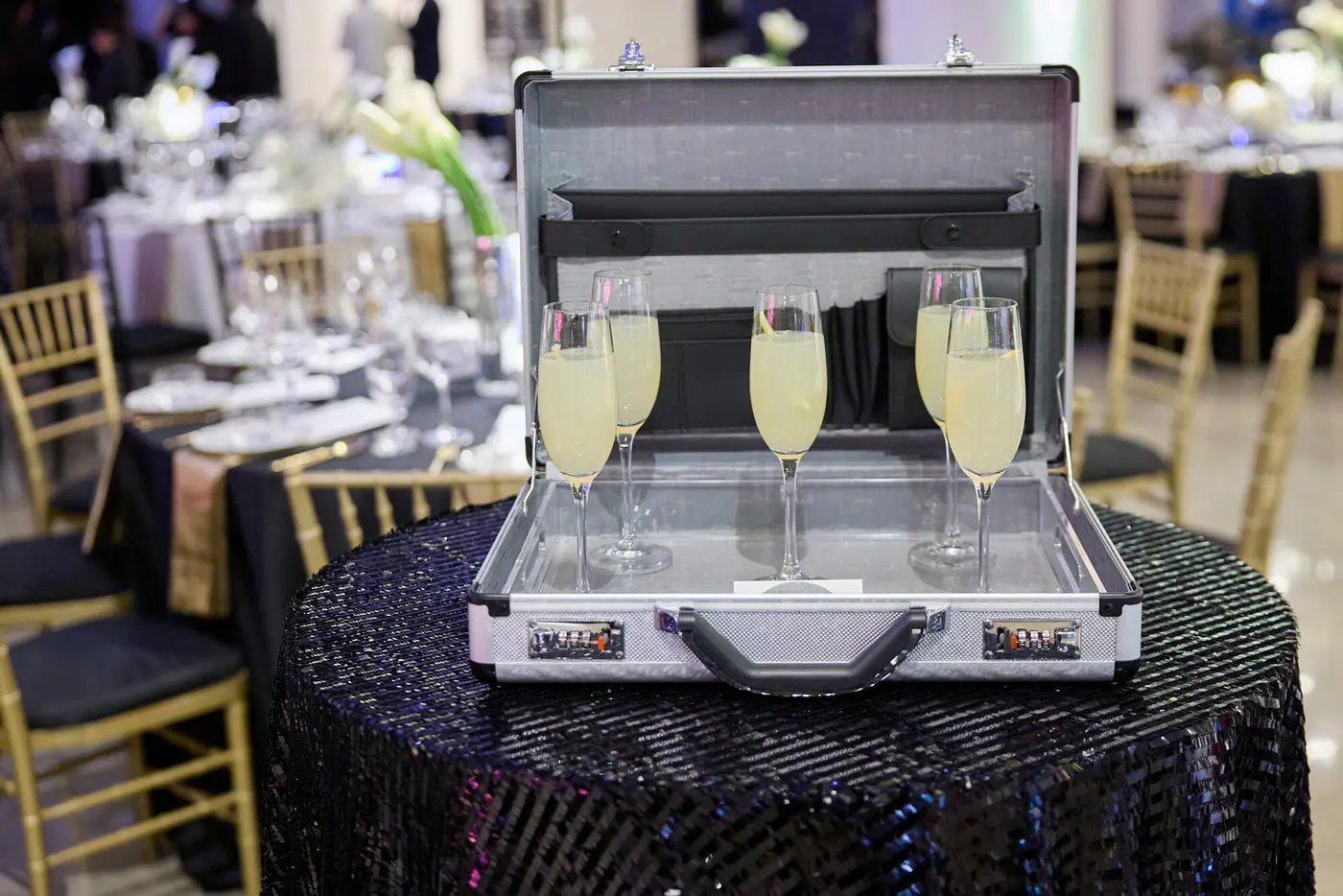 Champagne flutes inside an open silver briefcase at the 007 Science gala produced by Michigan Avenue Events
