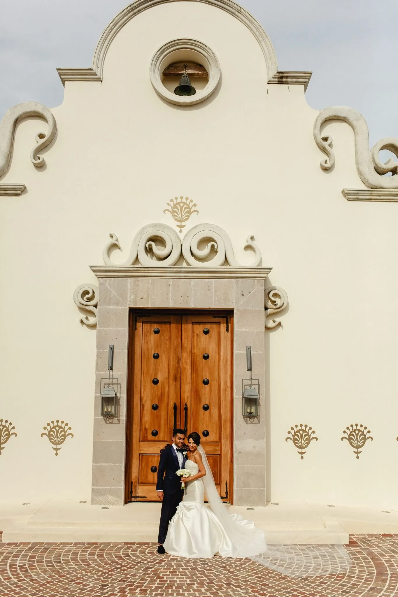 Lara Sofia and Atul at Spanish Colonial doors in gown and tuxedo